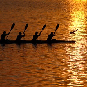 People paddle in a canoe as the sun sets over the River Ganges in Allahabad