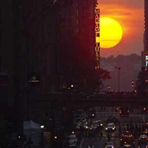 People take pictures of sunset on 42nd street, during the Manhattanhenge in New York