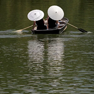 People protect themselves from the sun with parasols while rowing in Central Park