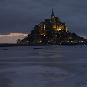 People sit on an embankment as the incoming tide surrounds the Mont Saint-Michel 11th