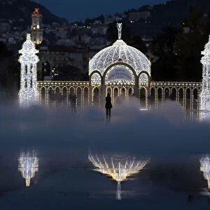People stand in the mist as they look at a replica of the casino along the Promenade