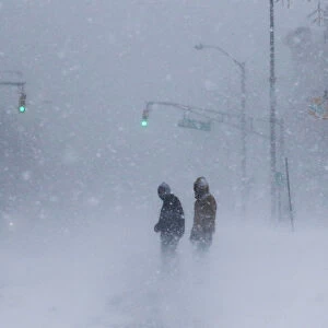 People struggle against wind and snow during Storm Grayson at the Jersey shore in Long