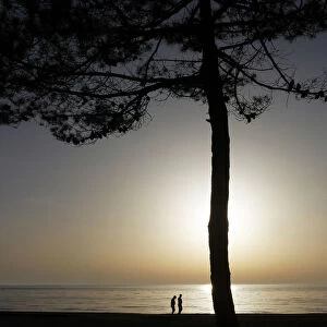 People walk along a beach facing the Adriatic sea near the city of Durres