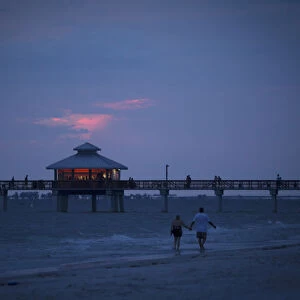 People walk along beach at twilight during the Labour Day long weekend in Ft Myers Beach