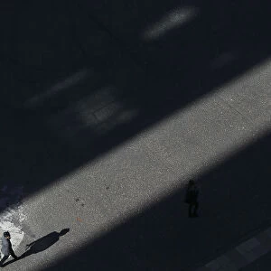 People walk though a shaft of sunlight in London