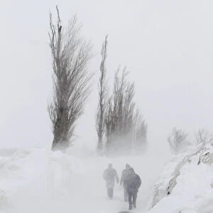 People walk on a snow-covered road near Glodeanu Silistea village