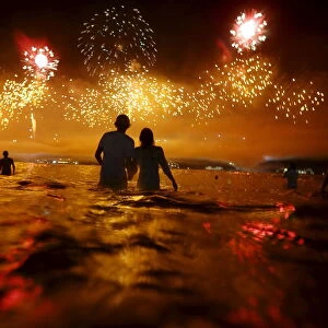 People watch as fireworks explode over Copacabana beach during New Year celebrations