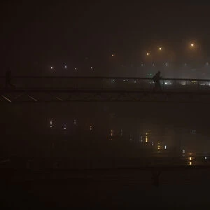A person crosses a bridge during heavy fog in Dublin