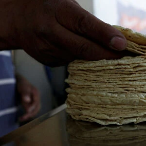 Person weighs a stack of freshly made corn tortillas at a tortilla factory in Mexico City