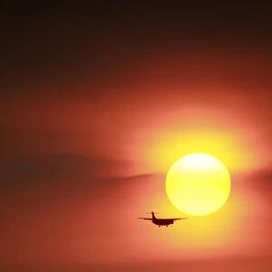 A plane flies past a setting sun near the Songshan airport in Taipei, Taiwan