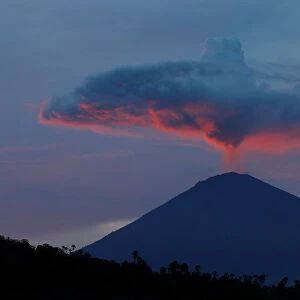 A plume of smoke above Mount Agung volcano is illuminated at sunset as seen from Amed