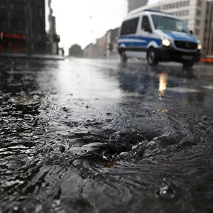 A police vehicle drives on a street during heavy rain in Frankfurt