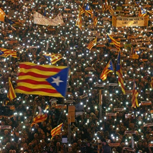 Protesters hold the lights of their mobile phones as they wave Estelada flags during a