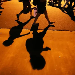 Protesters shadows mark the sidewalk as they march during another night of protests Protesters shadows mark the sidewalk as they march during another night of protests