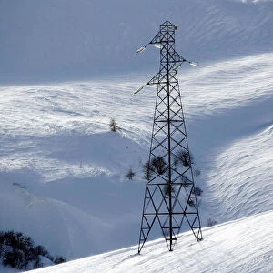 Pylon of high-tension electricity power lines is pictured on snow-covered mountain in