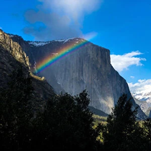 A rainbow is seen across the Yosemite Valley in front of El Capitan granite rock formation