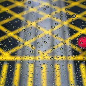 Resident walks across road under rainfall, seen through glass, in Hong Kong