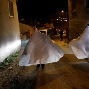Revellers wrapped in white sheets walk during the aeBocuk nightA Revellers wrapped in white sheets walk during the aeBocuk nightA