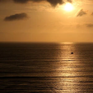 A sailboat sails during sunset in the Pacific Ocean in Lima