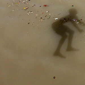 The shadow of a boy is seen as he jumps into the Ganges river to cool off on a hot summer