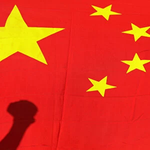 Shadow of clenched fist of protester is seen on Chinese national flag during anti-Japan