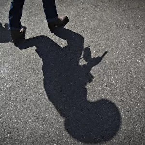 The shadow of a gunfighter is cast on the asphalt as competitors practice prior to