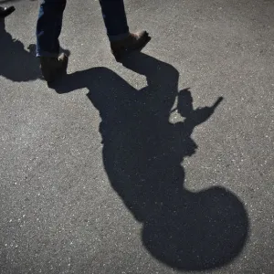 The shadow of a gunfighter is cast on the asphalt as competitors practice prior to