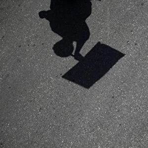 The shadow of a protestor holding a banner casts on the road during a May Day labour