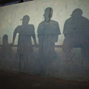 Shadows are cast on the wall of a stadium as people watch a traditional wrestling