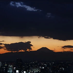 The silhouette of Japans highest mountain Mount Fuji is seen beyond buildings in Tokyo