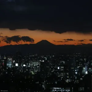The silhouette of Japans highest mountain Mount Fuji is seen beyond buildings in Tokyo