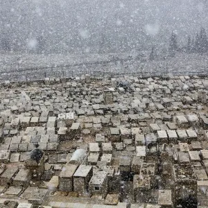 Snow falls on top of graves at the Mount of Olives cemetery in Jerusalem