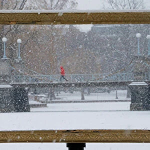 Snow falls through a picture frame in the Boston Public Garden during a winter storm in