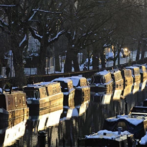Snow is seen on top of narrow boats are seen at sunset on Regents Canal in Little