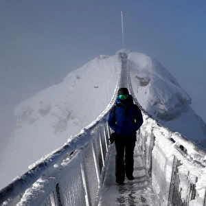 A snowboarder walks on the Peak Walk bridge at Glacier 3000 in Les Diablerets