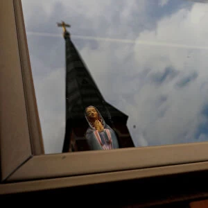 Statuette of Virgin Mary is seen inside of a house in front of Charles Borromeo Parish