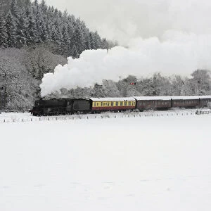 A steam train is seen running through a snow covered valley between Pickering