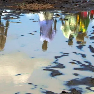 Sudanese are reflected in a pool of rain water in southern Sudan