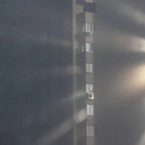 Sunlight reflects from windows of an apartment building on a foggy autumn day in Kiev