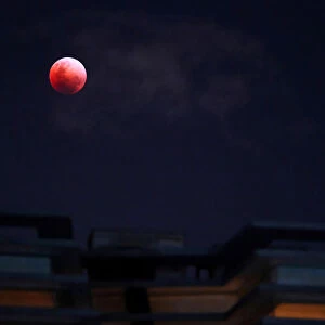 A Super Blue Blood Moon rises over an apartment block during a lunar eclipse in