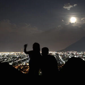 A supermoon rises while a couple takes a photo in Monterrey