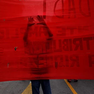 A supporter of the Communist party uses a scissors to make holes on a banner as he takes