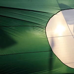 A supporter of opposition PAS is silhouetted on its giant flag as he campaigns on a