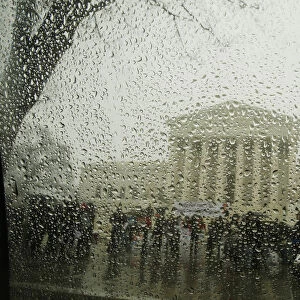 The Supreme Court is seen from within a car as snow melts on the window during a light
