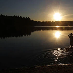 A swimmer wades into Walden Pond on a fall afternoon in Concord