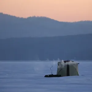 A tent of fishermen is seen on the ice-covered Yenisei River during sunset in A tent of fishermen is seen on the ice-covered Yenisei River during sunset in