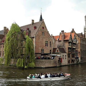 Tourists enjoy a boat ride on a canal of the old town in Bruges