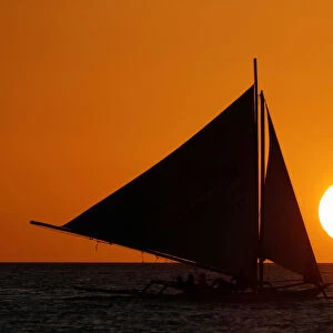 Tourists ride on a sailboat during sunset at Boracay in the Philippines