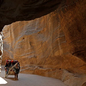 Tourists sit in a horse-drawn cart during a tour in the ancient city of Petra, south
