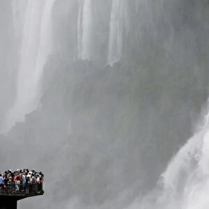 Tourists stand at the end of a catwalk on the Brazilian side of the Iguazu river to